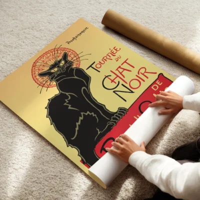 A person rolling up a vintage 'Tournee du Chat Noir' poster featuring a black cat on a golden background.