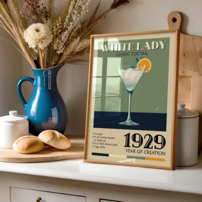 Poster of White Lady classic cocktail recipe in a kitchen setting, with a blue vase and baked goods in the foreground.