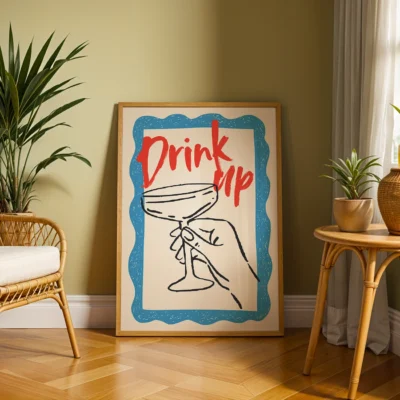 A framed artwork showing a hand holding a cocktail glass, with the text 'Drink up' in bold red letters on a blue background.