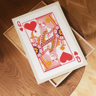 A Queen of Hearts playing card laying on a wooden table, showcasing colorful designs and patterns.