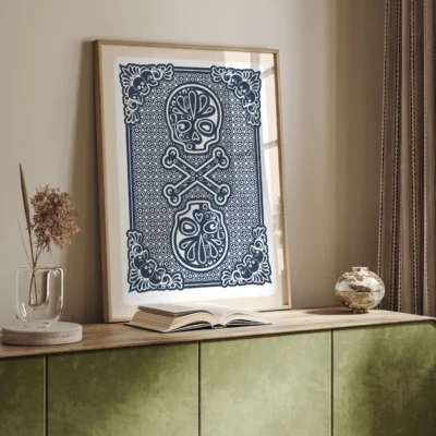 Framed artwork of two decorative skulls with crossed bones on a wooden table