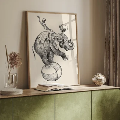 Illustration of an elephant balancing on a beach ball with a performer on its back, framed and displayed in a stylish room.