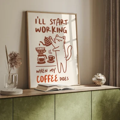 A framed motivational poster featuring a playful illustration of a cat pouring coffee with the text 'I'LL START WORKING WHEN MY COFFEE DOES.