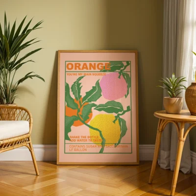 A framed poster art featuring oranges, with text saying 'ORANGE YOU'RE MY MAIN SQUEEZE', in a cozy room setting.