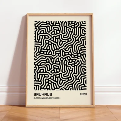 Wood-framed Bauhaus poster standing on floor against light wall