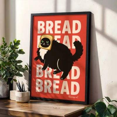 Black-framed "Bread" cat poster on sunlit desk with plants