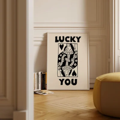 Black and cream Queen of Hearts poster standing on floor in minimalist interior, retro playing card design.