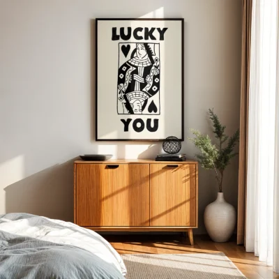 Black and cream Queen of Hearts wall art above wooden cabinet in mid-century modern bedroom.