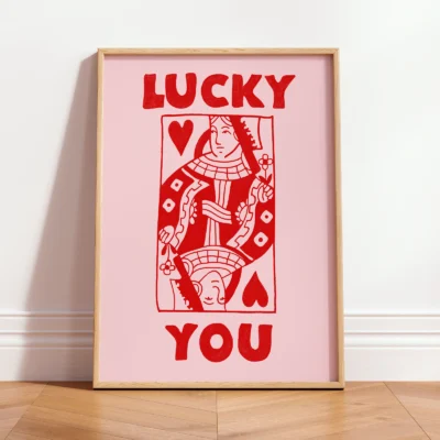 Framed red and pink Queen of Hearts poster leaning against wall, hand-drawn funky retro playing card style.