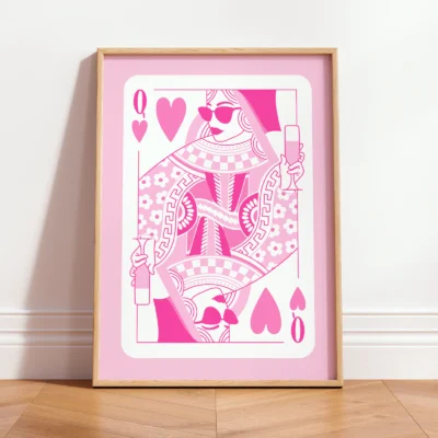 Pink and white Queen of Hearts art print leaning against wall, retro playing card style in minimalist interior.