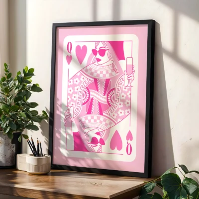 Pink and white Queen of Hearts poster in black frame, styled on shelf with plants in modern interior.