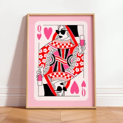 Pink and red Queen of Hearts art print in light frame, leaning against wall in minimalist interior.