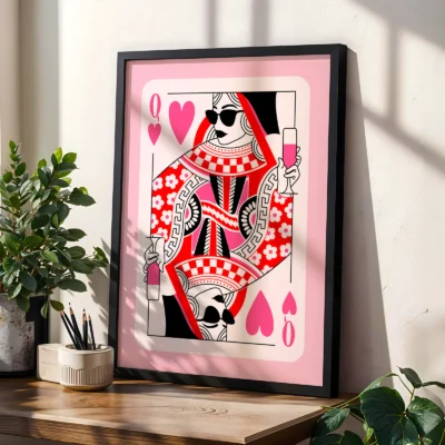 Pink and red Queen of Hearts poster in black frame, styled on shelf with plants in modern interior.