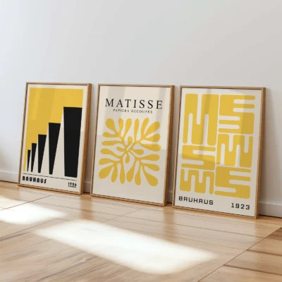 Yellow and black Bauhaus posters leaning on white wall in sunlit space