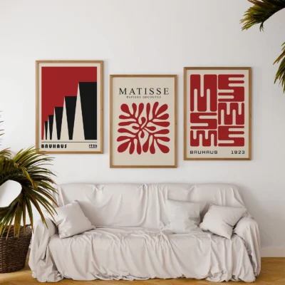 Famous Bauhaus posters in red and black above white couch with plants