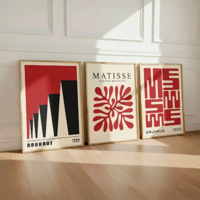Red Bauhaus posters leaning on wall in bright room with wooden floor