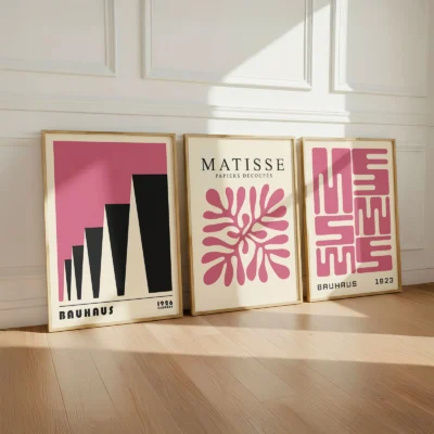 Pink Bauhaus posters leaning against white wall on wooden floor