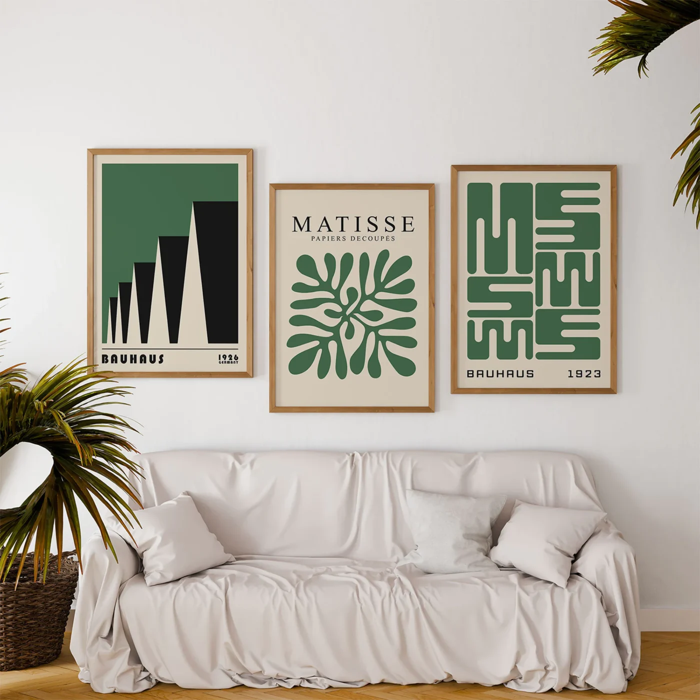 Green and black Bauhaus posters above sofa with plants in living room