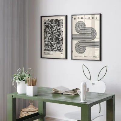 Small framed Bauhaus art prints on white wall above green table
