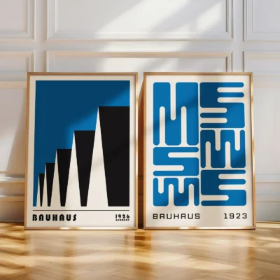 Two modern Bauhaus prints leaning against a white wall on wood flooring