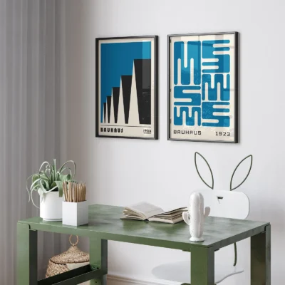 Two Bauhaus posters with blue and black graphics above a small green desk