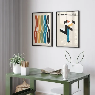 Bauhaus prints with colorful abstract forms above a small green desk