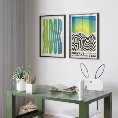 Two vertical Bauhaus prints with abstract waves and gradient sun above desk