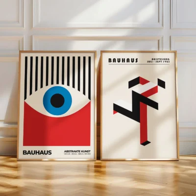Two Bauhaus posters with eye motif and abstract structure leaning on floor