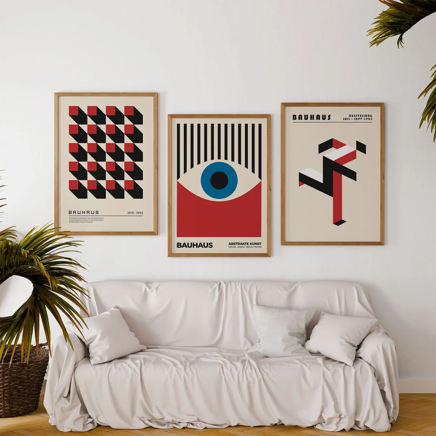 Set of three art prints with geometric Bauhaus designs above white sofa