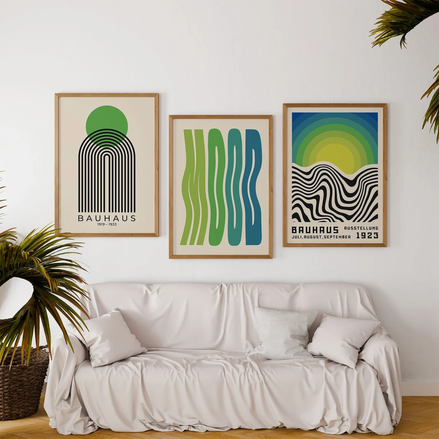 Mid century posters in green and blue above white sofa with plants
