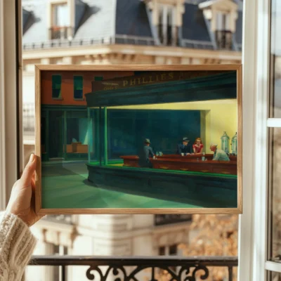 Person holding a framed Nighthawks art print on balcony