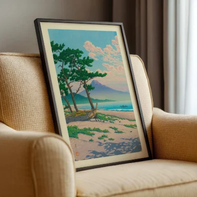Hasui Kawase art print resting on beige armchair, pastel landscape with sea and trees